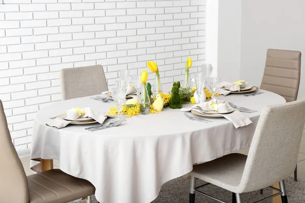 Festive dining table served for Easter celebration near white brick wall