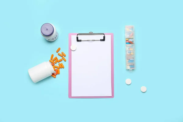 Blank clipboard with pills on blue background. World Health Day