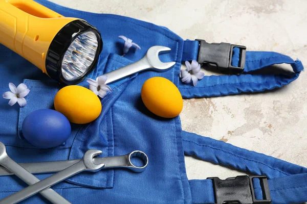 Plumber\'s uniform with tools, Easter eggs and flowers on grunge background, closeup