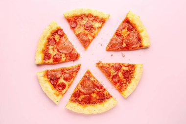 Slices of delicious pepperoni pizza on pink background