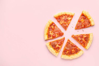 Slices of delicious pepperoni pizza on pink background