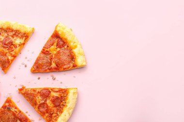 Slices of delicious pepperoni pizza on pink background