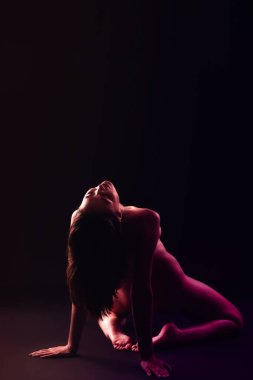 Toned portrait of naked young woman on dark background