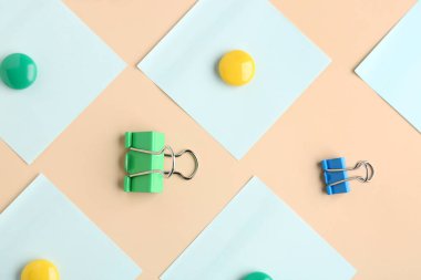 Composition with binder clips, magnets and  sticky notes on color background