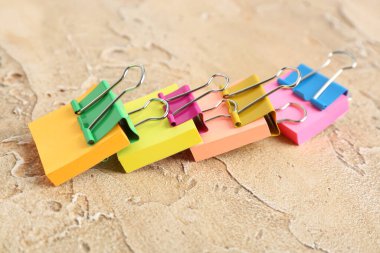 Sticky notes with colorful binder clips on color background