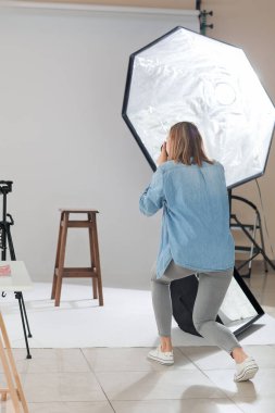 Female photographer with professional camera working in studio