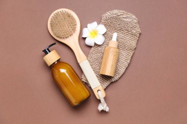 Composition with massage brush, glove and bottles of cosmetic products on color background