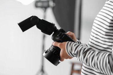 Young male photographer with professional camera in studio, closeup