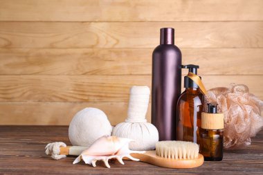 Set of bath supplies, cosmetic products and seashell on wooden table