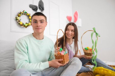 Happy young couple with baskets of Easter eggs in bedroom