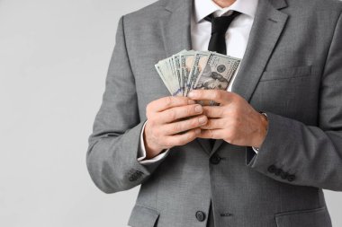 Businessman with bribe on grey background, closeup