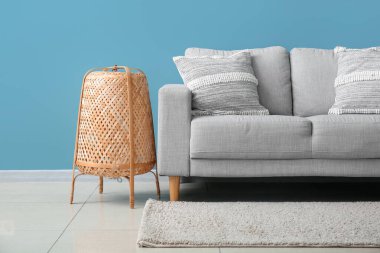 Stylish decorative pillows on cozy grey sofa near blue wall