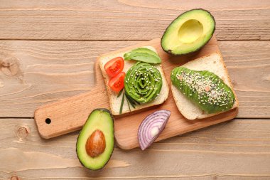 Board with delicious avocado toast on brown wooden background