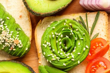 Delicious avocado toast on wooden board, closeup