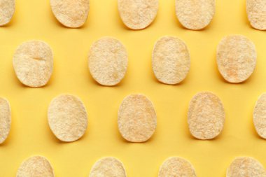 Many delicious potato chips on yellow background