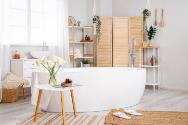 Interior of bathroom with ranunculus flowers in vase on table