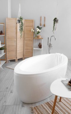 Interior of bathroom with ranunculus flowers in vase and bathtub