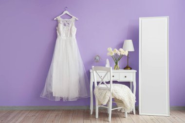 Interior of dressing room with flowers in vase, table and wedding dress