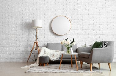 Interior of living room with ranunculus flowers in vase, sofa and armchair