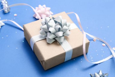Gift box with bows and ribbon on blue background, closeup