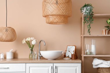 Counters with sink, flowers and mirror in interior of bathroom