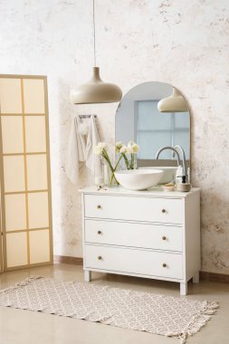 Interior of light bathroom with sink, drawers and folding screen