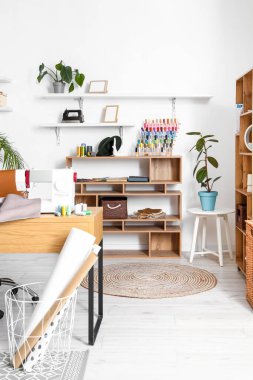 Interior of modern atelier with tailor's workplace and shelving units