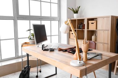 Tailor's workplace with computer, lamp and male accessories in atelier