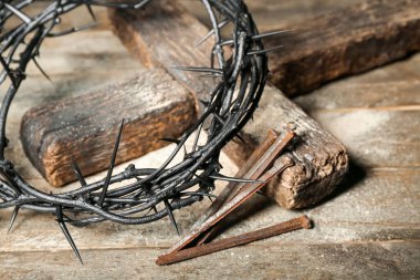 Crown of thorns, nails and cross on wooden table, closeup