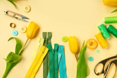 Frame made of tailor's supplies and tulips on yellow background. Hello spring