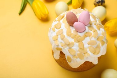 Easter cake, painted eggs and tulip flowers on yellow background