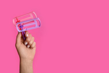 Woman with Jewish rattles for Purim holiday on pink background