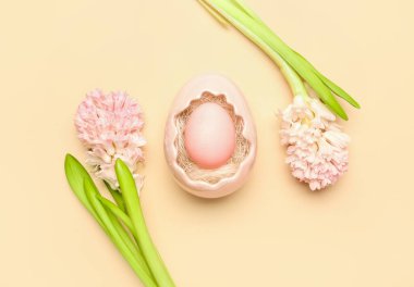 Composition with beautiful hyacinth flowers and Easter egg in decorative basket on beige background