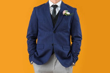 Young guy in prom suit and with boutonniere on yellow background