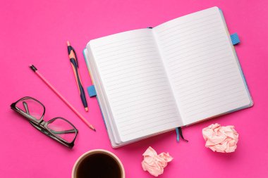 Blank notebook, pen, eyeglasses and cup of coffee on pink background