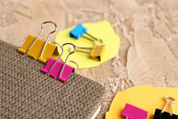 Notebook, binder clips and sticky notes on color background, closeup
