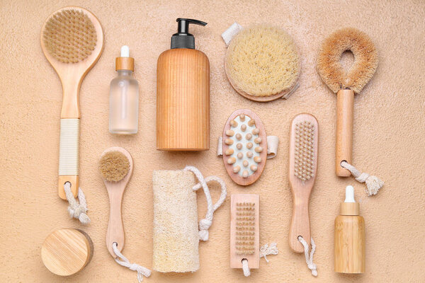 Набор массажных кистей с губкой для ванны и косметическими средствами на цветном фоне