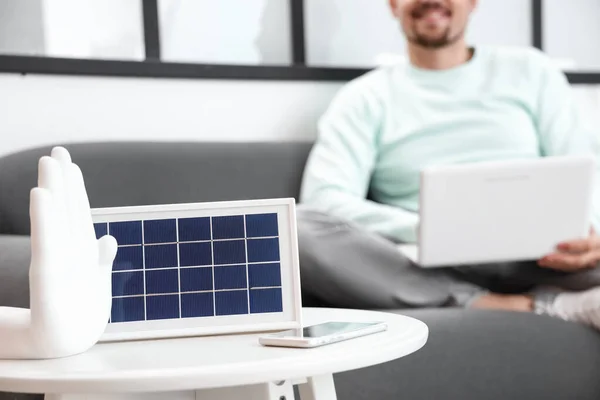 Portable solar panel and mobile phone on table in room, closeup