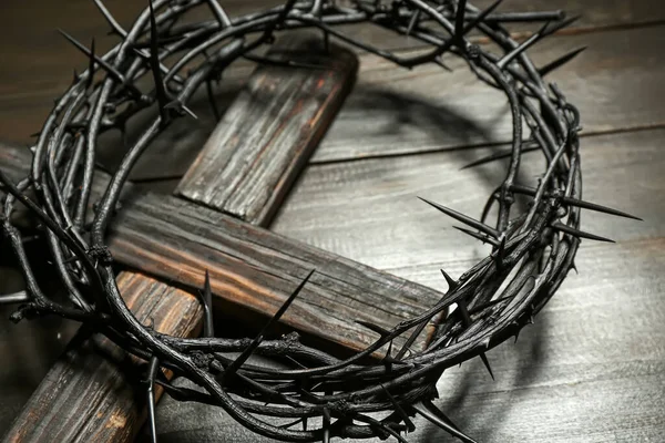 Crown of thorns with cross on dark wooden background, closeup