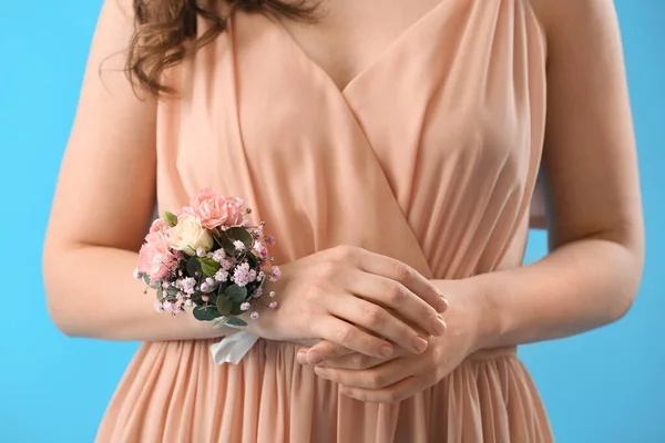 Young woman in prom dress with corsage on blue background, closeup