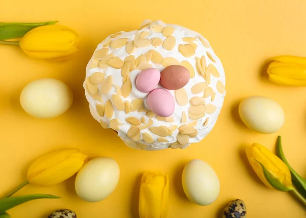 Composition with Easter cake, painted eggs and tulip flowers on yellow background