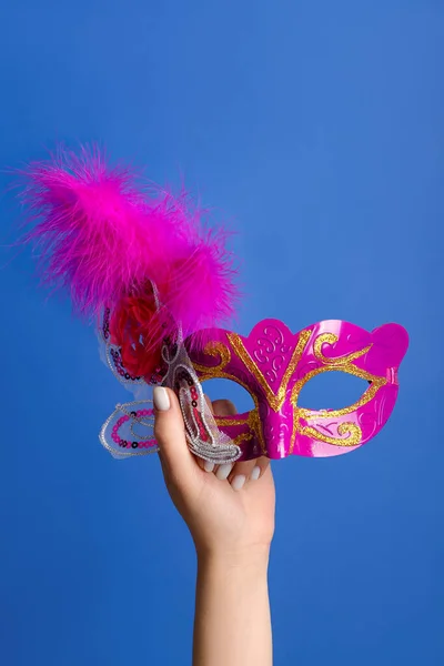 Woman with carnival mask for Purim holiday on blue background