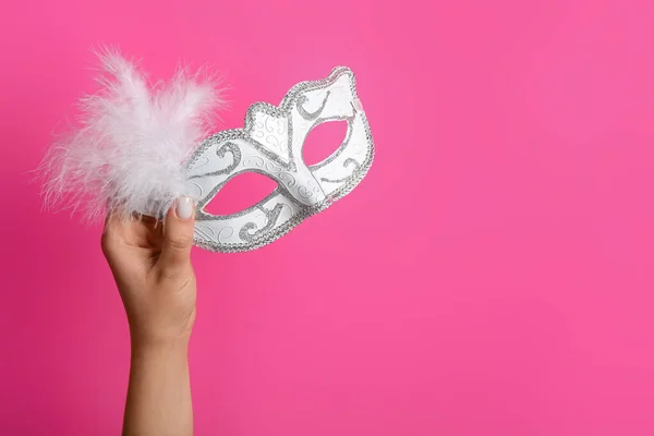 Woman with carnival mask for Purim holiday on pink background