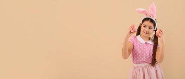 Tavşan kulaklı küçük kız ve bej arka planda Paskalya yumurtaları ve mesaj için yeri var.