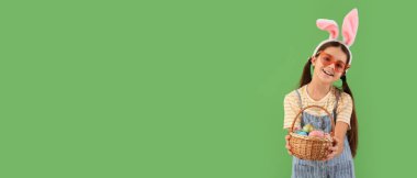 Tavşan kulaklı komik kız ve yeşil arka planda Paskalya sepeti. Mesaj için yeri var.