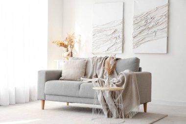 Gri kanepe ve yaratıcı sanat eserleriyle modern oturma odasının içinde.