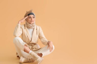 Bej arka planda oturan şık Müslüman kadın