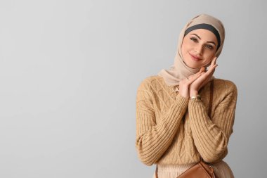Açık arkaplanda bej tesettürlü şık Müslüman kadın
