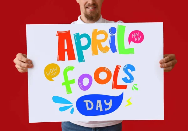 Young Man Holding Poster Text April Fools Day Red Background — Stock Photo, Image