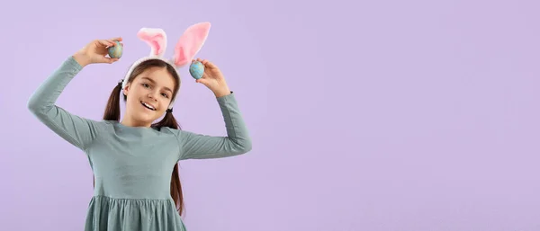 小さな女の子とともにウサギの耳とイースターの卵上のライラックバックでテキストのためのスペース — ストック写真